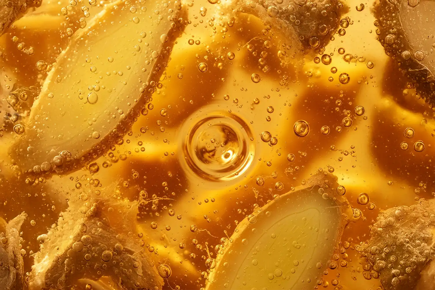 Racine de gingembre en infusion liquide, bulles fines flottant, représentant son action stimulante et antioxydante.