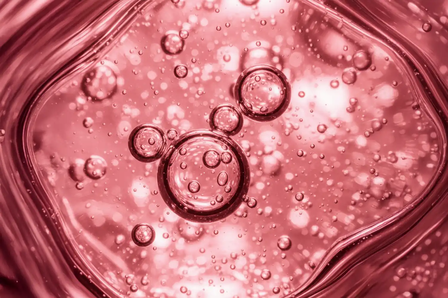 Gel rose en macro close-up avec bulles fines, représentant le panthénol (vitamine B5) apaisant et réparateur.