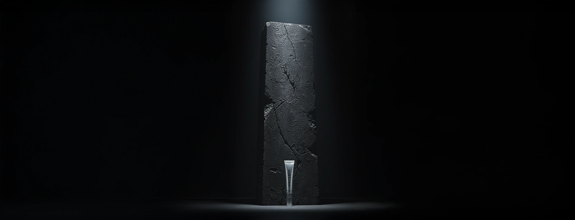 Gloss repulpant NEMESYS posé devant un bloc de pierre noire craquelée, éclairage dramatique qui souligne la puissance et la sobriété de la formule.