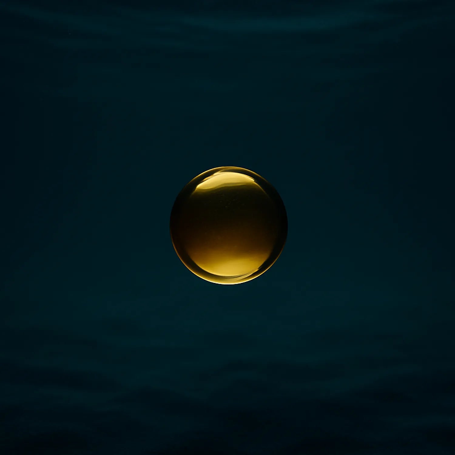 Goutte d’or suspendue dans une matière sombre, illustrant l’action antioxydante invisible et réparatrice de la vitamine E dans le gloss Ocean Bloom de NEMESYS.